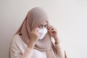 muslimsk flicka som bär en kirurgisk mask på pastellbakgrund.