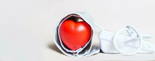 röd hjärta och vit elektronisk tonometer isolerat på beige bakgrund foto