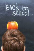 ett äpple på en barnets huvud nära svarta tavlan. tillbaka till skola begrepp bakgrund foto