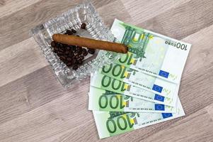 100 eurosedlar och askkopp med cigarr foto