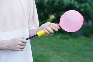 blåser rosa ballong förbi hand luft pump, blåses upp luft till ballong begrepp, barn spela, leksak och Utrustning till spela roligt spel eller förbereda fest. foto