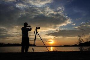 silhuett av fotograf med sin solnedgångshandkontroll. foto