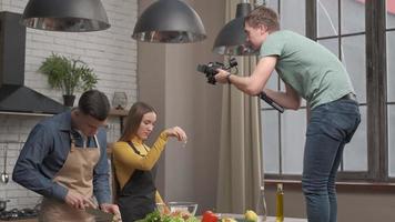 videograf som filmar köksscenen. förälskat par förbereder en hälsosam måltid hemma i köket