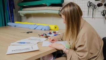 närbild av kvinnlig designer med penna och pappersark för modeskisser. skräddare kvinna skapar design av ny klädkollektion på studio foto