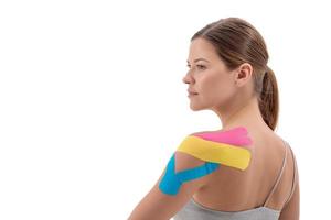färgad kinesioterapitape på ung idrottskvinna axel isolerad på vit bakgrund. kopiera utrymme