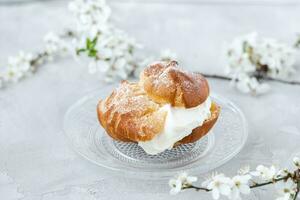 choux bulle med vispad grädde och socker pulver på topp. choux bakverk efterrätt. franska grädde puff foto