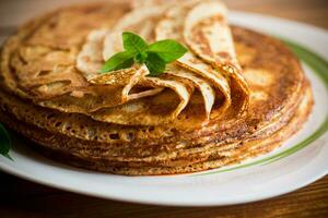 massa av pannkakor tunn pannkakor i en tallrik, på trä- tabell. foto