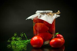 konserverad mogen röd tomater med kryddor i en stor glas burk. foto
