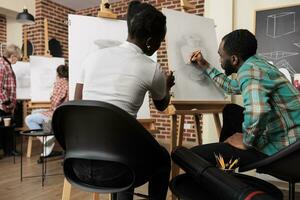 ung afrikansk amerikan par man och kvinna teckning tillsammans på grupp konst klass i modern studio. människor lära sig ny Kompetens med familj eller vänner, kreativ hobby för par till stärka obligation foto