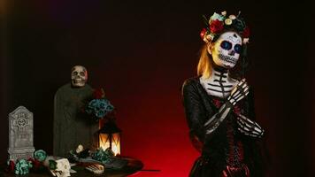 flörtig kvinna bär santa muerte kropp konst i studio, verkande glamorös på dag av de död- mexikansk halloween firande. ritual skalle kropp konst, Framställ med svart ro och blommor krona. foto
