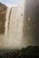 selektiv fokus av stor vattenfall i Island, vatten ström löpning ner från scandinavian isig klippor. spektakulär arktisk skgafoss kaskad faller av kullar kant formning isländsk landskap. foto