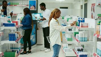 afrikansk amerikan kvinna kontroll lådor av medicin från apotek hyllor, ser till köpa farmaceutisk Produkter från affär. kvinna kund tar läkemedel och vitaminer från apotek. foto