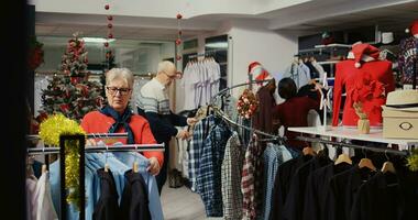 kunder roaming runt om upptagen Kläder Lagra dekorerad med jul ornament under vinter- Semester säsong. klienter handla för gåvor under xmas PR försäljning i mode boutique foto