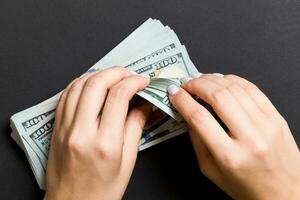 topp se av en affärskvinnas händer räkning ett hundra dollar sedlar på färgrik bakgrund. Framgång och rikedom begrepp foto