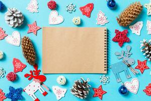 topp se av anteckningsbok omgiven med ny år leksaker och dekorationer på blå bakgrund. jul tid begrepp foto