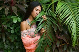 mode porträtt av asiatisk kvinna Framställ i tropisk trädgård. bär boho klänning. foto