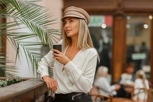 romantisk Söt blond kvinna njuter varm kaffe utomhus. bär beige trendig basker. höst humör. foto