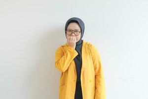 skön ung asiatisk muslim kvinna, bär glasögon och gul blazer med rädd ansikte uttryck foto