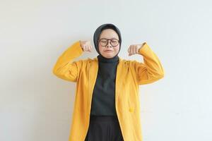 skön ung asiatisk muslim kvinna, bär glasögon och gul blazer med ledsen uttryck foto
