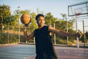 svart man håller på med sporter, spelar basketboll på soluppgång, aktiva livsstil, solig sommar morgon- foto