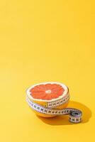 frukt orange är insvept med mätning tejp på gul bakgrund. foto