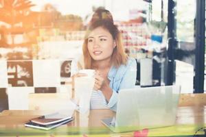 ung hipsterkvinna som håller en kopp kaffe och jobbar lite. foto
