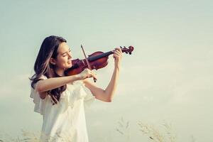 vacker kvinna som står och spelar fiol på ängen foto