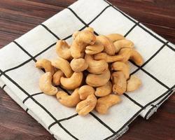 cashewnötter i bordsduk på träbord foto
