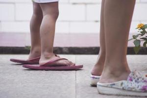 en liten flickas fötter med överdimensionerade sandaler som följer med sin mamma foto