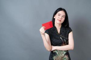 asiatisk kvinna bär kinesisk traditionell klänning med rött kuvert foto