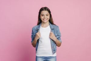 leende, positiv tjej poserar på en rosa bakgrund foto