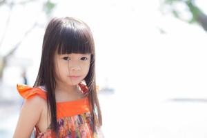 porträtt liten flicka asiat av ett leende stående i parken foto