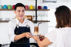ung barista förbereder isad latte för att betjäna kunden i caféet