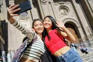 Lycklig asiatisk kvinna turister tar själv porträtt på smartphone mot katedral av granada i Spanien foto