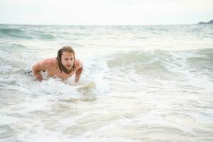 ung man surfing på de strand har roligt och balansering på de surfingbräda foto