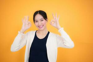 porträtt av en Lycklig ung asiatisk kvinna isolerat på gul bakgrund foto