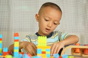 asiatisk pojke spelar med pedagogisk leksaker där är många skön färger på de tabell i de hus. foto