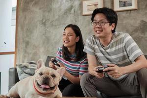 asiatiskt par spelar tv -spel och husdjur i närheten.