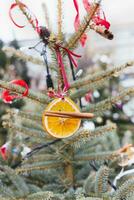 naturlig dekoration tillverkad av orange skivor och jul kryddor på band på jul träd. diy jul dekoration. miljö, återvinna, återanvändning och noll avfall begrepp. selektiv fokus foto