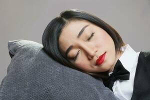 trött sömnig kvinna receptionist med stängd ögon liggande huvud ner på kudde. restaurang catering service ung attraktiv utmattad asiatisk servitris sovande och avkopplande närbild foto