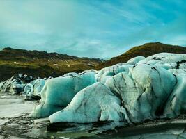 skön is bitar med blå och grön toner dyka upp i majestätisk Vatnajokull glaciär massa, frysning kall vattnen av isländsk kust. Drönare skott av skön rutt med isberg och isig hög klippor. foto