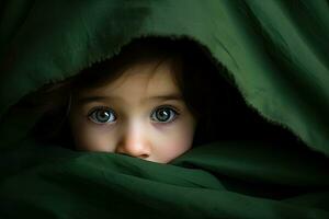 porträtt av en söt liten flicka dölja under en grön filt, söt liten bebis flicka är dölja under en grön filt i säng, ai genererad foto