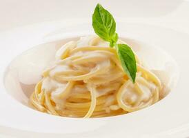 spaghetti med vit grädde sås på vit tallrik foto