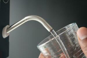 vatten häller från en kran kran i en glas, dricka ren vatten begrepp foto