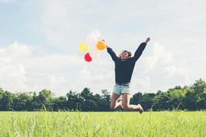 vacker kvinna som håller ballong på grönt gräs som springer och hoppar foto