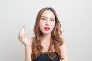 porträtt vacker asiatisk kvinna som gör upp och använder rött läppstift på vit bakgrund