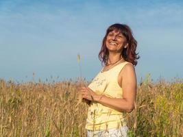 leende kvinna i sommarfältet vid solnedgången, positivitetskoncept