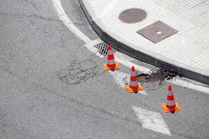 skadad stadsväg markerad med kottar som väntar på reparation
