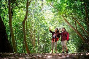 två unga asiatiska kvinnliga hipster vandring i skogen foto