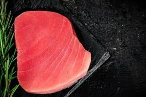 rå tonfisk på en sten styrelse med rosmarin. foto